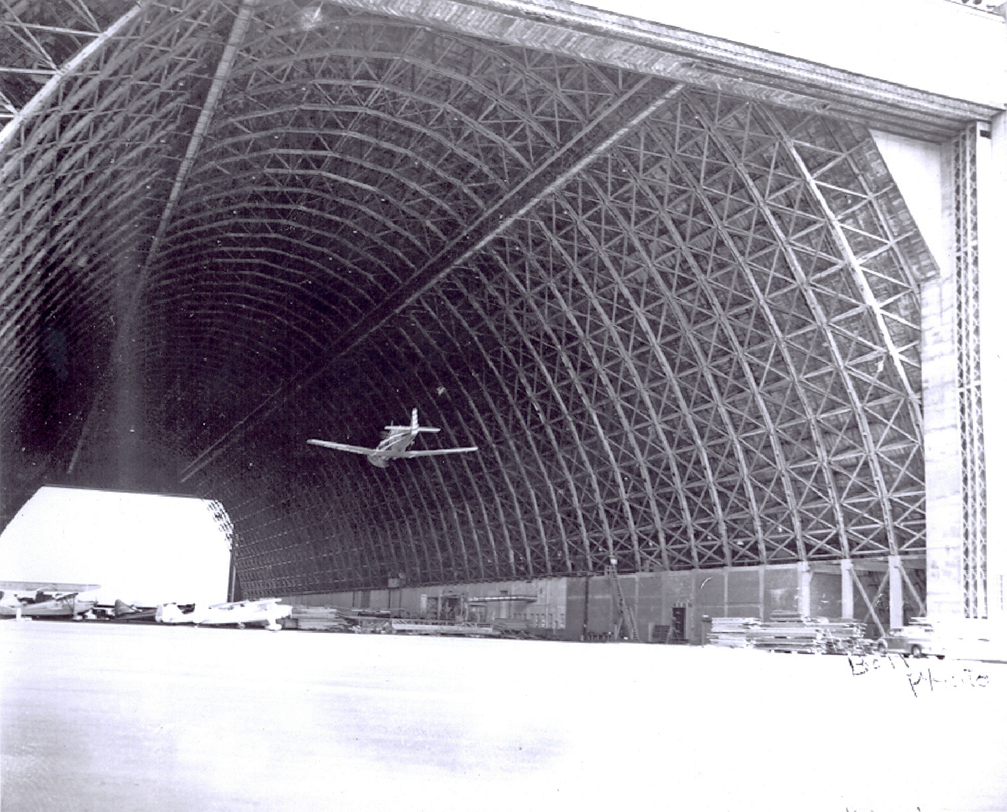 Airplane flying through open hangar bay at Naval Air Station Tillamook