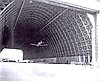 Airplane flying through open hangar bay at Naval Air Station Tillamook